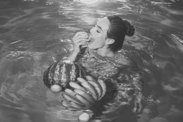 Ragazza con frutta tropicale in piscina. ragazza nuotare con anguria e banana in acqua — Foto Stock