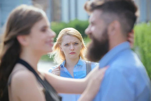 A jealous girlfriend. Unhappy girl feeling jealous. Bearded man cheating his girlfriend with another woman. Romantic couple of man and woman dating. Jealous woman look at couple in love on street — Zdjęcie stockowe