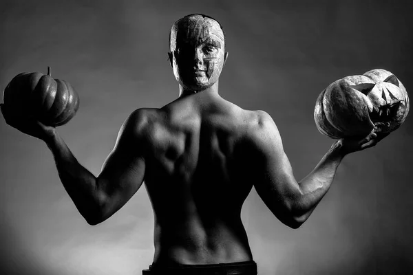 Homme musclé en masque avec des citrouilles — Photo