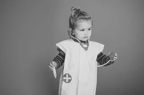 Ребенок в форме врача со стетоскопом, шприц на синем фоне — стоковое фото