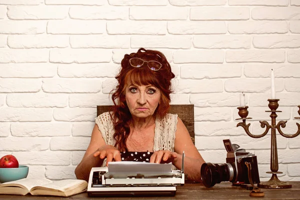 Age barrier. Journalist work in vintage office. Old woman work in writer office. Senior woman type on retro typewriter. Senior writer at desk. Female reporter or journalist writing on typewriter