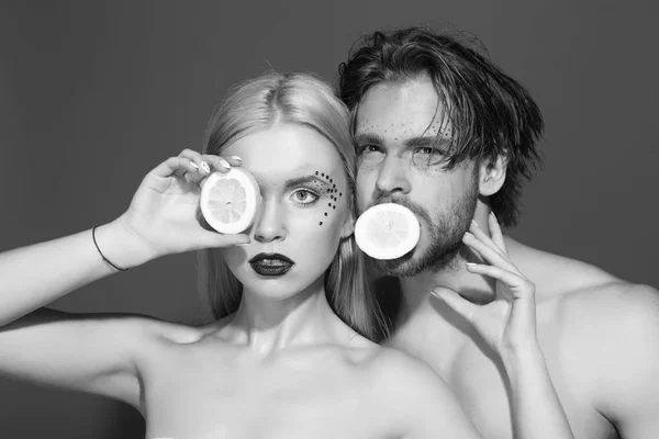 woman and man with makeup hold lemon