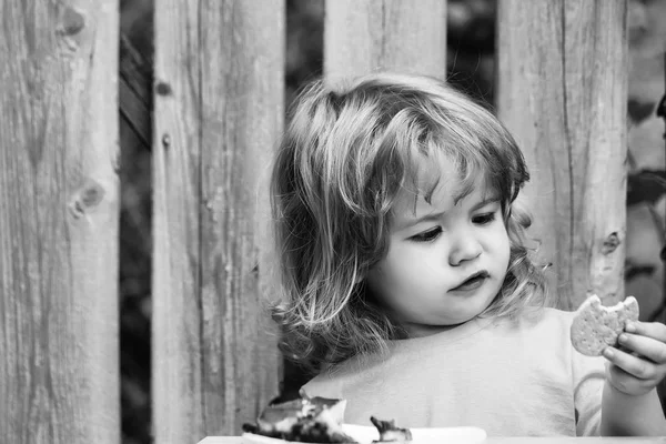 Malý chlapec jíst koláč u dřevěného plotu — Stock fotografie