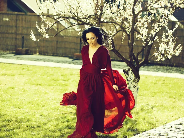 Жінка в червоній сукні біля цвітіння — стокове фото