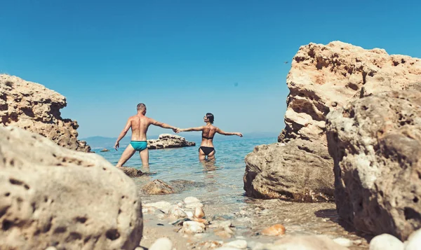 Couple amoureux se détendre sur la plage. Famille et Saint Valentin. Relations amoureuses de couple profitant de la journée d'été ensemble. Vacances d'été et vacances de voyage. Femme sexy et l'homme se tiennent dans l'eau de mer . — Photo