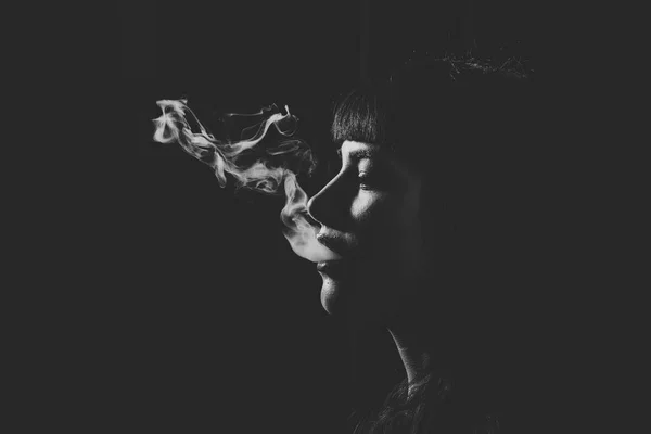 Frauenkopf mit Rauch im Mund auf schwarzem Hintergrund. — Stockfoto