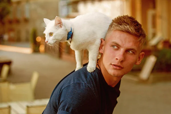 Wanting to know about everything. Cat stands on back of his owner. Happy man on walk with cat pet. Muscular man hold cute pedigree cat. Happy cat owner with muscular look