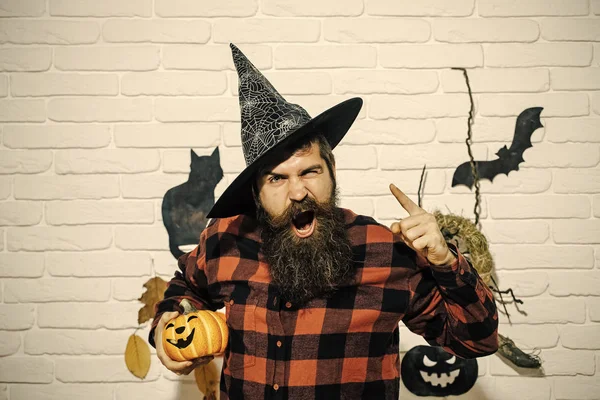 Halloween man in witch hat shouting with pumpkin