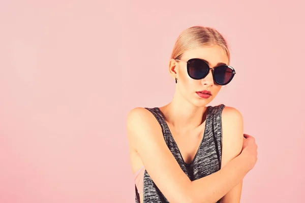 Närbild porträtt av blond modell med hästsvans i Melerad Grå ärmlös blus bär stora svarta solglasögon isolerad på rosa bakgrund. Sommar eyewear mode — Stockfoto