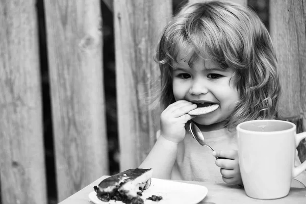 Kleine jongen eten taart in de buurt van houten hek — Stockfoto