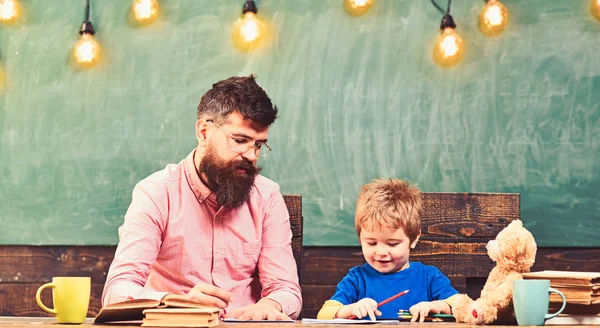 Insegnante e ragazzino che scrivono lettere in un copybook. Ragazzo carino che disegna un quadro con matite colorate. Lezione d'arte all'asilo — Foto Stock