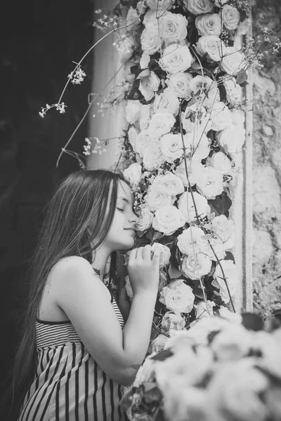 Ung flicka i sommar klänning lukt gul ros, våren — Stockfoto