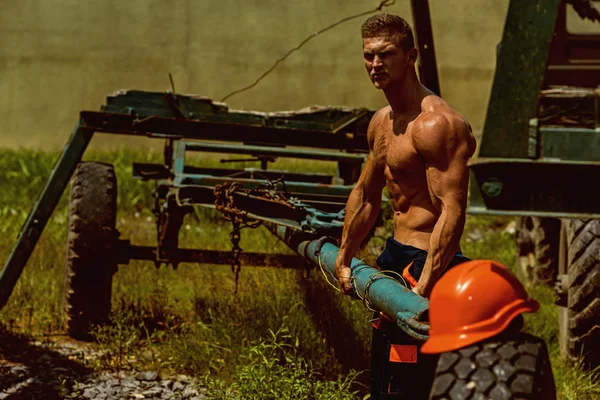 Constructor concept. Constructor pull truck trailer. Constructor worker with six pack and ab muscular torso. Strong constructor on construction site — Stock Photo, Image