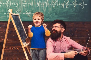 Mutlu çocuk okulda görev tamamlanıyor. Heyecanlı çocuk gülümseyen öğretmen yanında duruyor. Ders eğlenceli