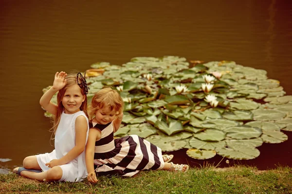 Menina mão onda na lagoa com flores de lírio de água — Fotografia de Stock