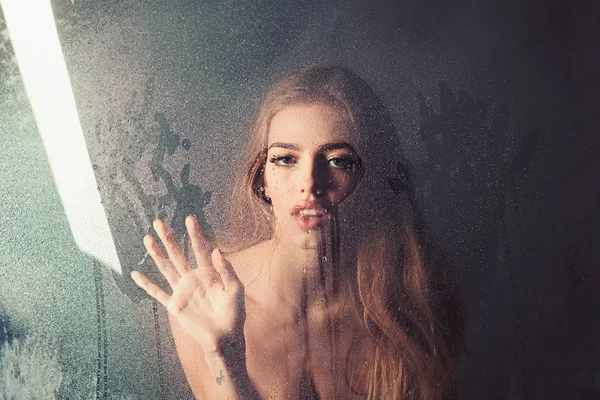 Rain drops on window glass in heart shape. Sexy woman behind plastic sheet with water drops. Window with water drops before girl with makeup. Shower and hygiene spa treatment. Fashion beauty and love. — Stock Photo, Image