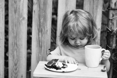 küçük çocuk ahşap çit yakınındaki pasta yemek
