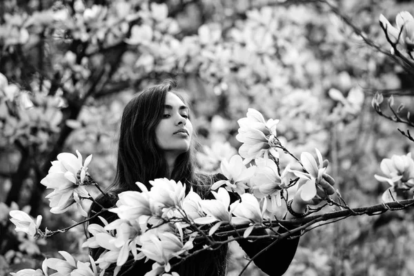 Kobieta z brunetka, długie włosy, pozowanie o drzewa magnolii — Zdjęcie stockowe