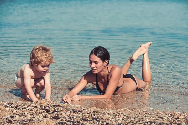 Madre e hijo pequeño hacen castillo de arena en la playa . — Foto de Stock