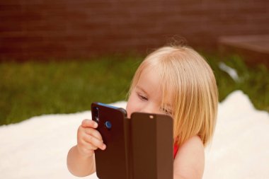 Cep telefonu bağımlılık. Küçük çocuk yapmak telefon görüşmesi. Küçük kız kullanım cep telefonu. Sarı saçlı kız çocuk cep telefonuyla konuşmak. Çocuklar için yeni teknoloji. En iyi saç sevinç