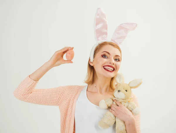happy woman in bunny ears with toy. Spring holiday. Girl with hare toy. Woman in rabbit bunny ears. Happy easter. Egg hunt. Easter eggs as traditional food. Easter preparations
