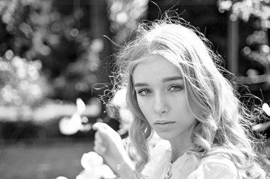 Kız rüya gibi yüzündeki defocused kameraya doğa arka plan, ihale sarışın görünüyor. Bayan park güneşli bahar gününde yürür. Güneşli bir gün kavramı. Genç kadın zevk Bahçe doğada.