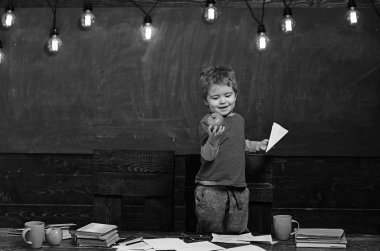 Elinde lezzetli apple bakarak boy gülümseyerek. Sarışın çocuk kağıt uçak holding. Masanın ayakta mutlu çocuk