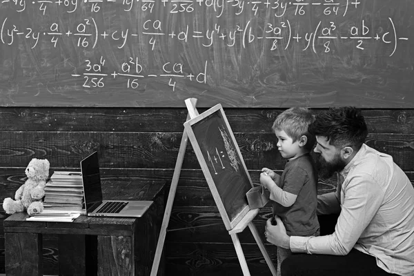 Okulda öğretmen ile öğrenci. Yan görünümü baba ve oğul aritmetik öğrenin. Güzel bir çocuk denkleme açıklayan baba — Stok fotoğraf