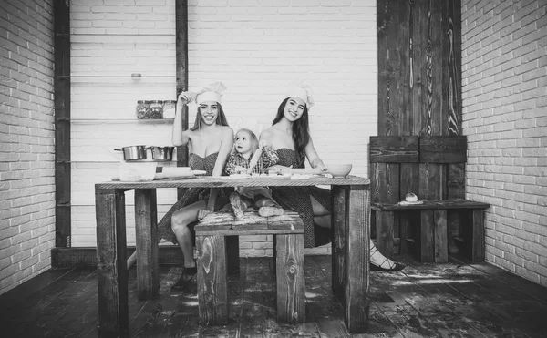 Jongen en twee meisjes zitten op de keukentafel — Stockfoto