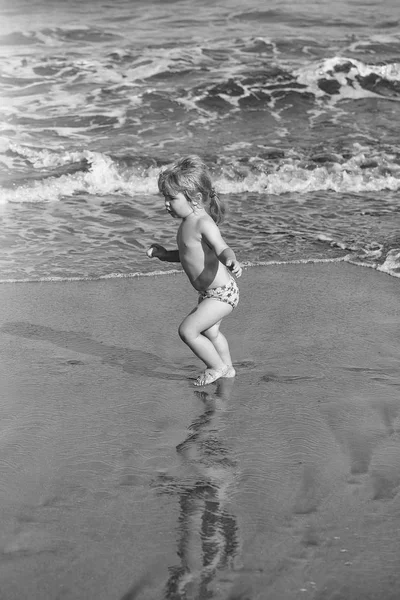 Lindo bebé alegre corre sobre arena mojada a lo largo del mar — Foto de Stock