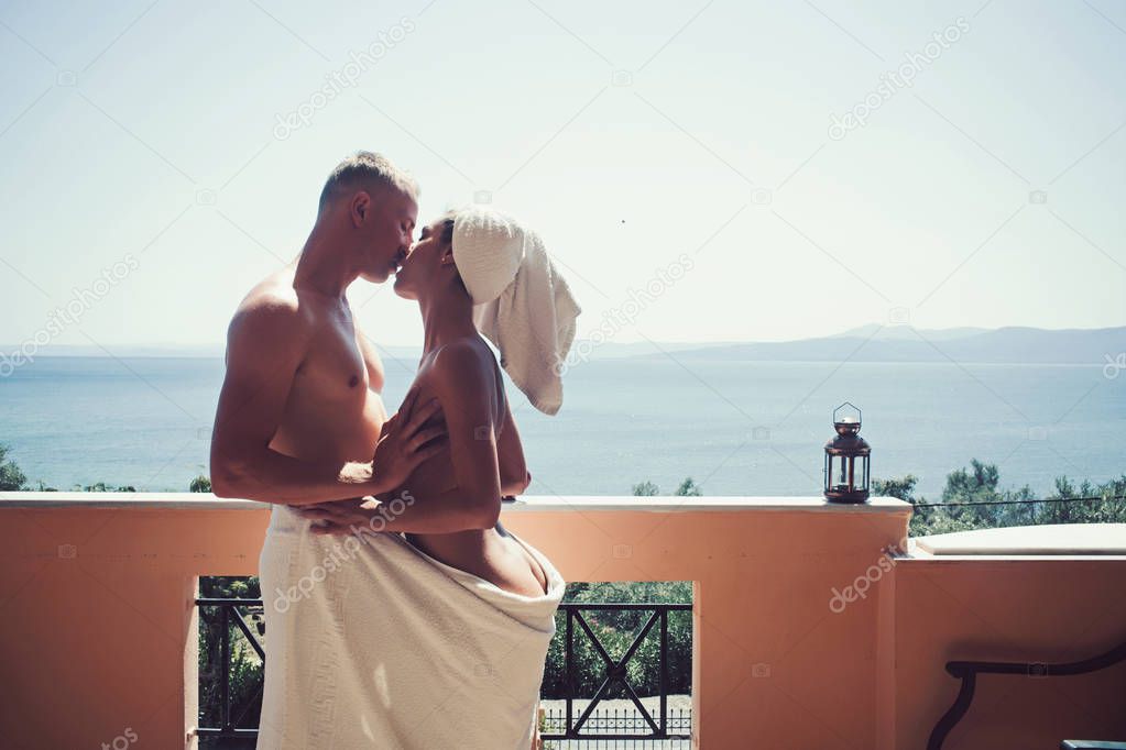 couple in love wrapped in a towel, hugging and kissing on the balcony.