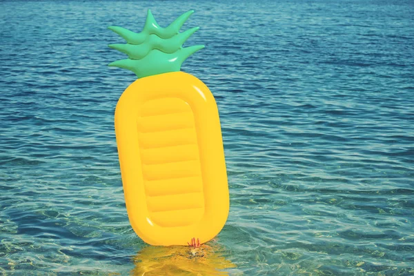 Pineapple inflatable mattress on sea water background. Summer vacation and travel to ocean. activity and joy on beach with air mattress. Maldives or Miami beach water. Caribbean sea in Bahamas.