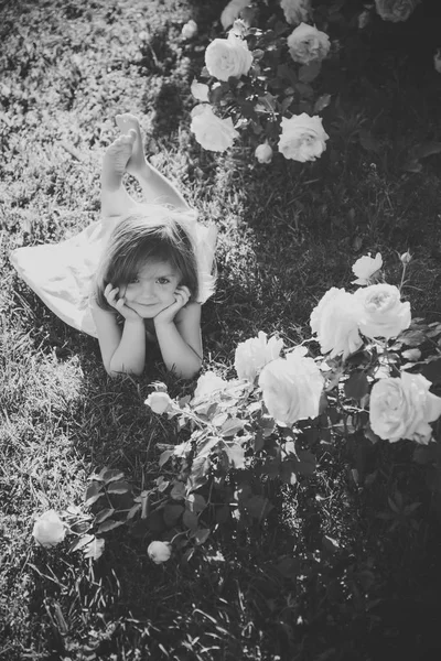 Criança com sorriso bonito em flores florescentes rosa — Fotografia de Stock