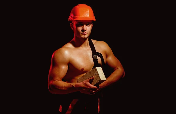 Quand il s'agit de construction, nous faisons tout. Homme travailleur tenir la brique dans les mains musclées. Travailleur de la construction ou constructeur au travail sur le chantier. Travailleur de maçon. Musclé homme fait travail de maçonnerie — Photo