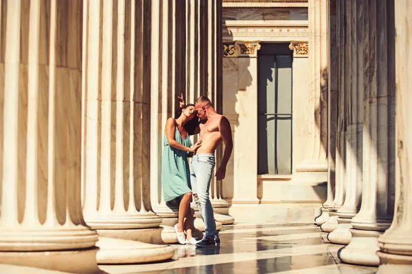 Loving couple standing in the columns in sunlight. — Stock Photo, Image