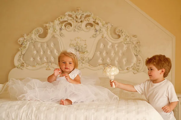 Acconciatura glamour. Bambina fiore indossare corona di capelli. Page boy con acconciatura bionda tenere mazzo di nozze. Bambini pronti per la cerimonia nuziale. Sviluppo dei bambini. Buoni giorni di capelli — Foto Stock