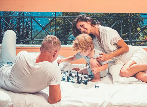 I bambini giocano a scacchi con padre e madre. bambino con i genitori giocare a scacchi sul balcone estivo . — Foto Stock