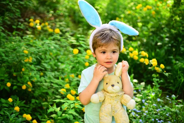 Konijn kind met bunny oren. Haas speelgoed. Egg hunt op voorjaar vakantie. hou van Pasen. Vakantie met het gezin. Kindje jongen in het groene woud. Vrolijk Pasen. Jeugd. Ester bunny hunt begint — Stockfoto