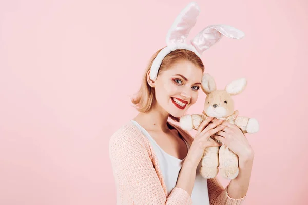 happy woman in bunny ears with toy. Spring holiday. Girl with hare toy. Woman in rabbit bunny ears. Happy easter. Egg hunt. Easter eggs as traditional food. copy space. Pretty bunny