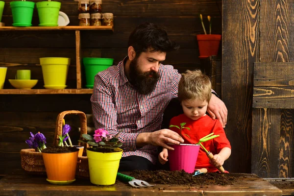 happy gardeners with spring flowers. Family day. Greenhouse. Flower care watering. Soil fertilizers. Father and son. bearded man and little boy child love nature. Gardening is my passion.