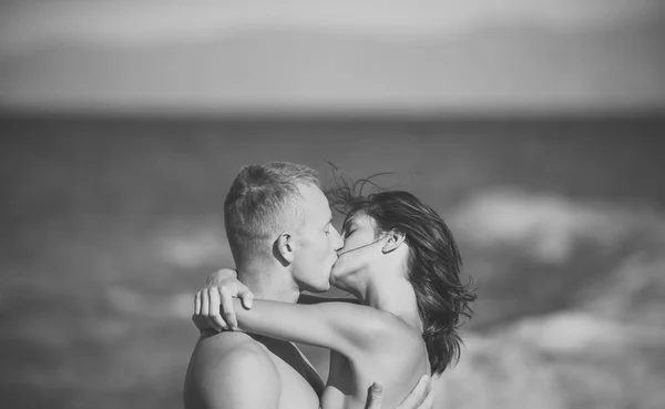 Casal apaixonado beijando à beira-mar. Família feliz passar o tempo juntos, abraço e beijo, fundo da superfície do mar. Conceito de lua de mel. Sensual casal atraente nu em rostos apaixonados . — Fotografia de Stock