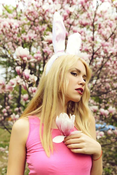 Jonge vrouw met bunny oren met magnolia bloem — Stockfoto