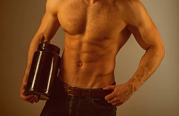 Dieta energética. Un hombre con seis abdominales. El hombre fuerte tiene botellas de vitaminas. Nutrición con vitaminas. Estimular el crecimiento muscular con esteroides anabólicos. La hormona anabólica aumenta la fuerza muscular. Dieta saludable — Foto de Stock