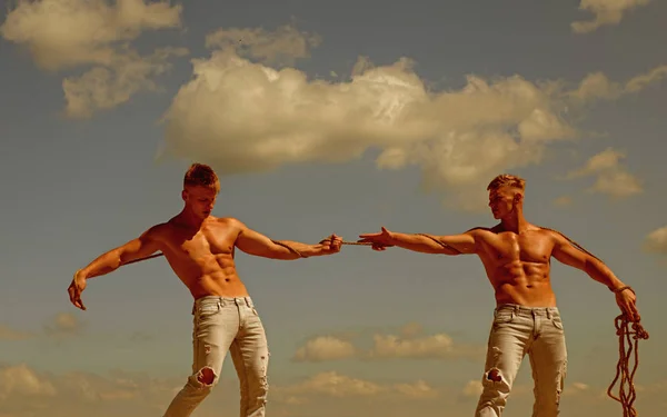 Opposites in sport. Men shows off their strength against competitors. Athletic twins on opposite sides. Twins competitors with muscular bodies. Strong men pull rope with muscular hand strength — Stock Photo, Image