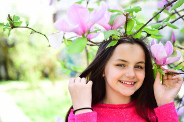 Bahar zamanı geldi. Sevimli kız bahar manzara üzerinde gülümseyen mutlu. Çiçeklenme tree yakınındaki güzel kız Manolya Çiçeği tadını çıkarın. Çok güzel bir gülücük ver çiçek açması çiçeklerle parkta. Bahar sevinçleri dolu
