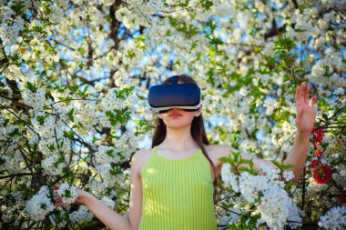 Hayal yaşıyor. Genç Bayan giyim vr gözlük Bahar Bloom. Yenilikçi vr teknolojisi. Sanal gerçeklik kulaklık güzel bir kız. Bahar bahçe oyunda sevimli kız. Sanal teknoloji simülasyon.