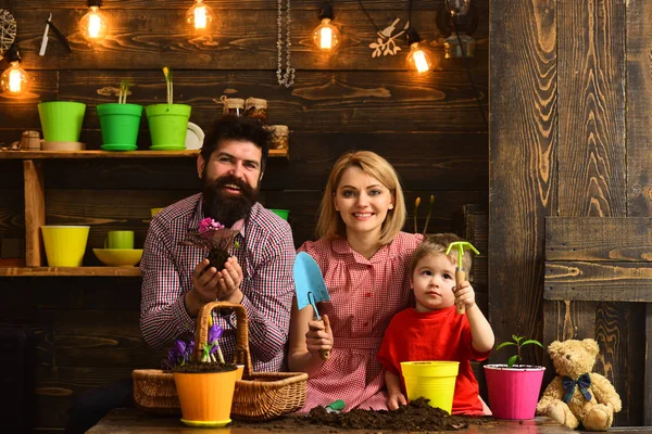 Vater und Sohn mit Mutter. Familientag. Gewächshaus. zufriedene Gärtner mit Frühlingsblumen. Blumengießen. Bodendünger. Frau, Mann und kleines Kind lieben die Natur. Mein Zuhause ist meine Burg — Stockfoto