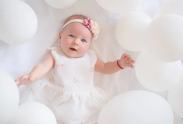 Look over there. Small girl. Happy birthday. Portrait of happy little child in white balloons. Sweet little baby. New life and birth. Childhood happiness. Family. Child care. Childrens day