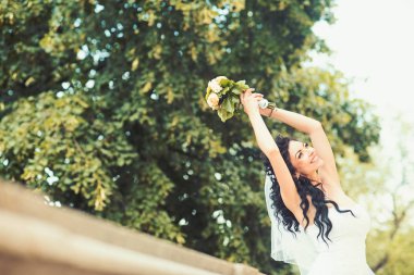 Oldukça mutlu gelin gül buketi ile lüks elbiseli