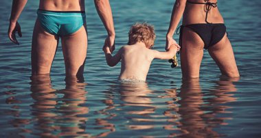 Mutlu aile - baba, Anne, bebek evlat sahilde günbatımı deniz boyunca suda. Seyahat ve aktif yaşam tarzı. Anne ile çocuk yaz tatil.